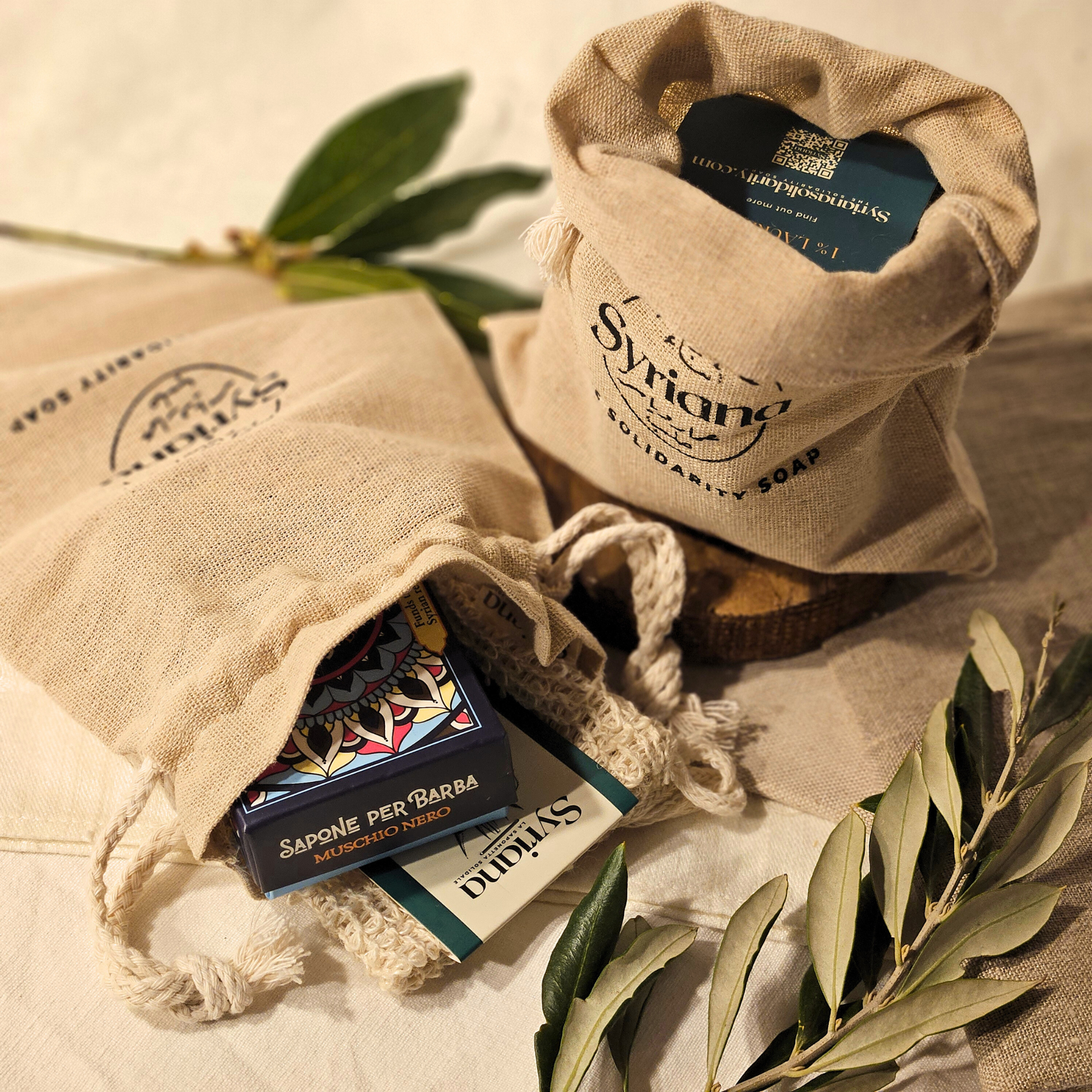Open linen gift bag revealing Syriana soap box inside with olive leaves styling