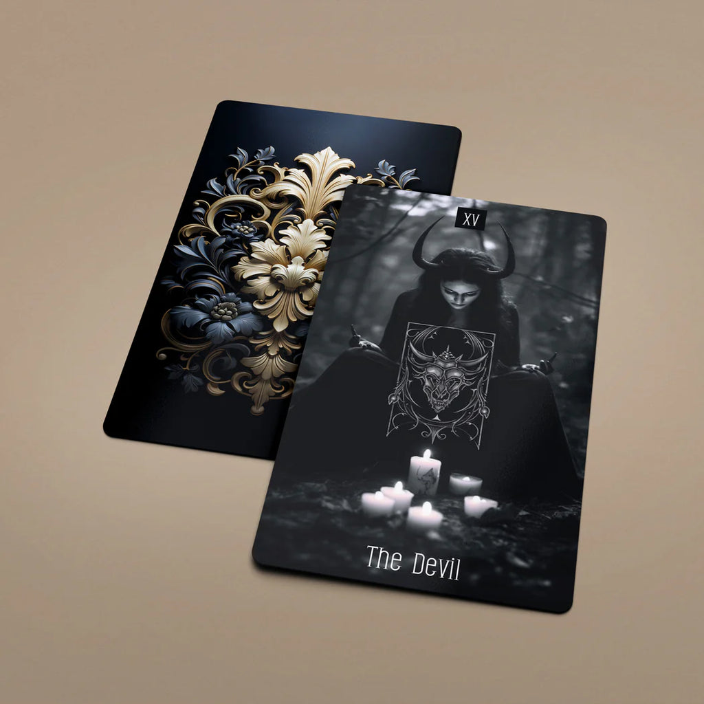 Dark Beauty Tarot card The Devil lying flat next to the black and gold card back design